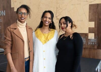 Three women smiling together indoors.