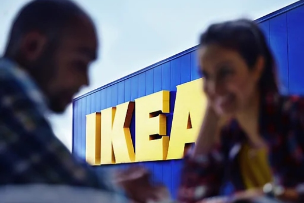 A man and woman smile with the IKEA sign in the background