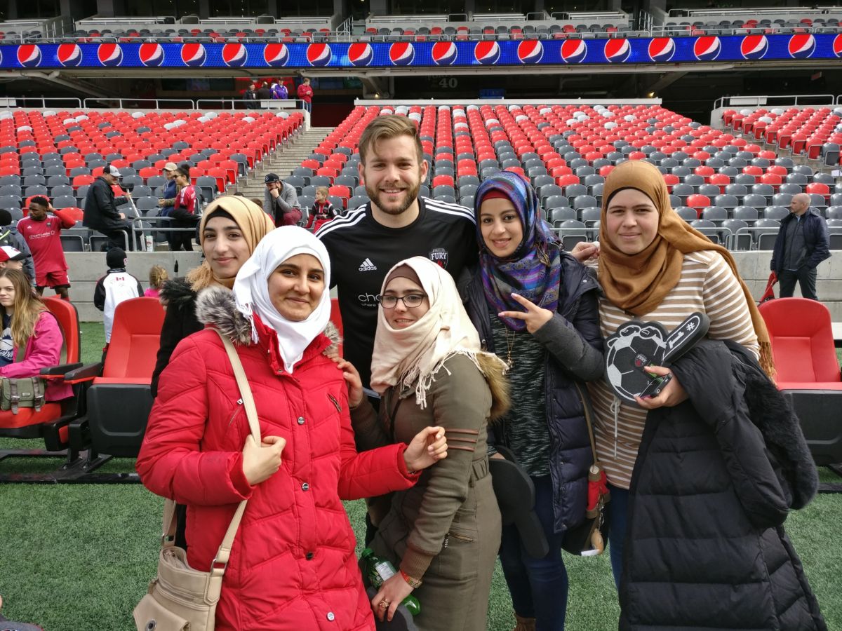 A group of youth newcomers pose with a player from the Ottawa Fury.