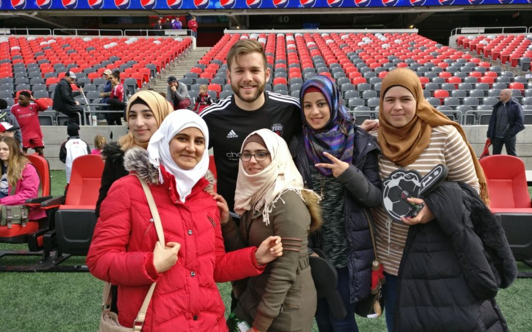 Young women pose with soccer player