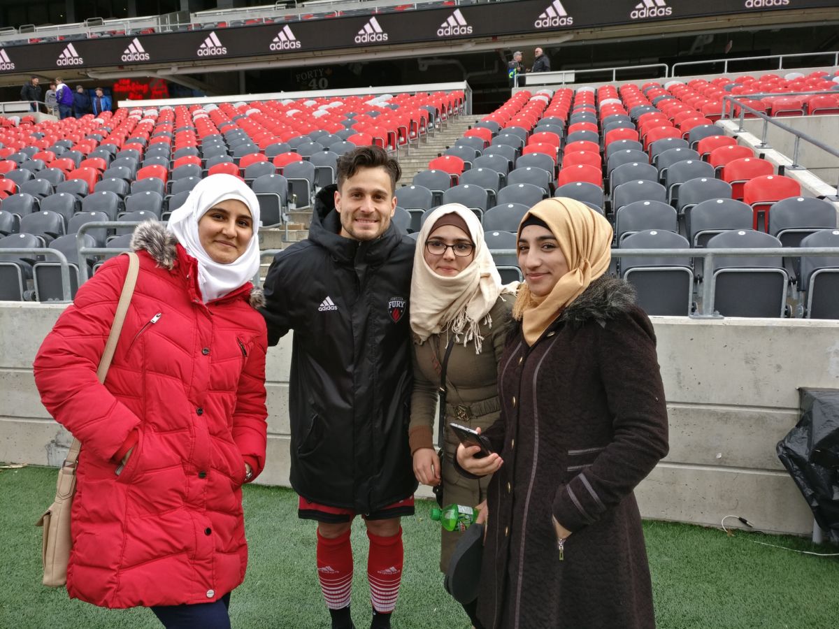 A group of youth newcomers pose with a player from the Ottawa Fury.