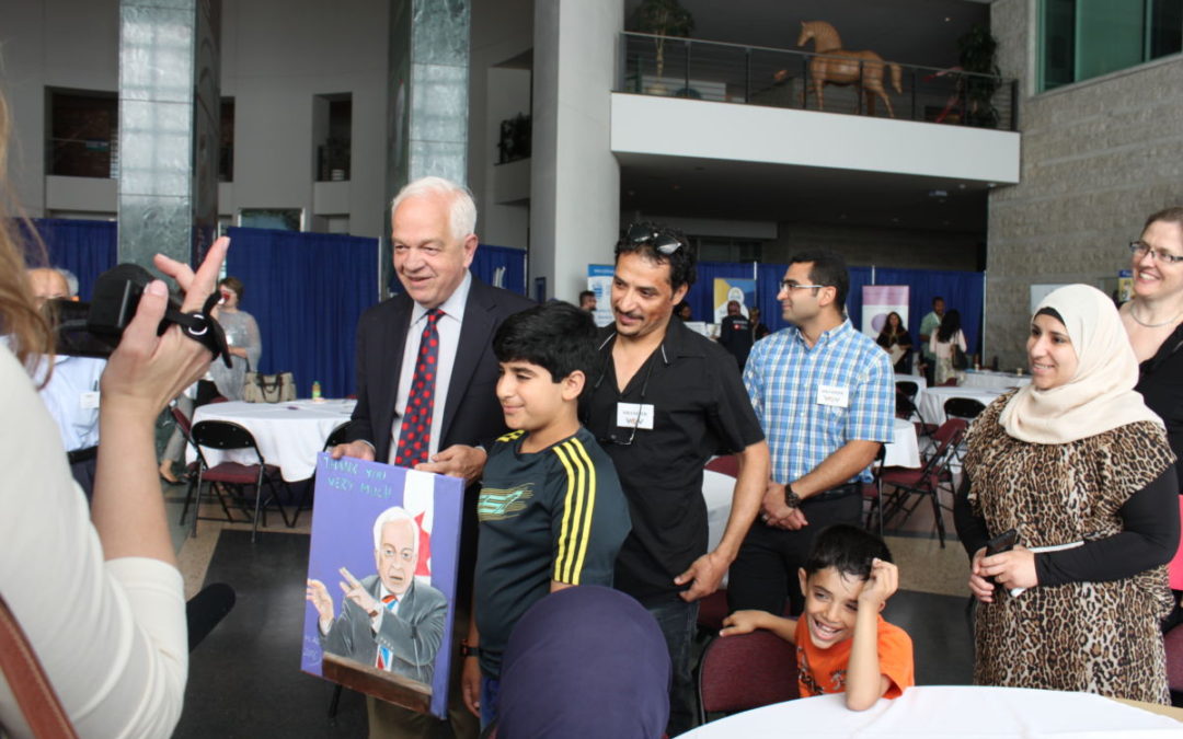 Immigration Minister John McCallum holds a painting Hamza Ali, 13, presented him with as his father Mohammad Ali looks on at an event in Ottawa, Monday June 20, 2016.