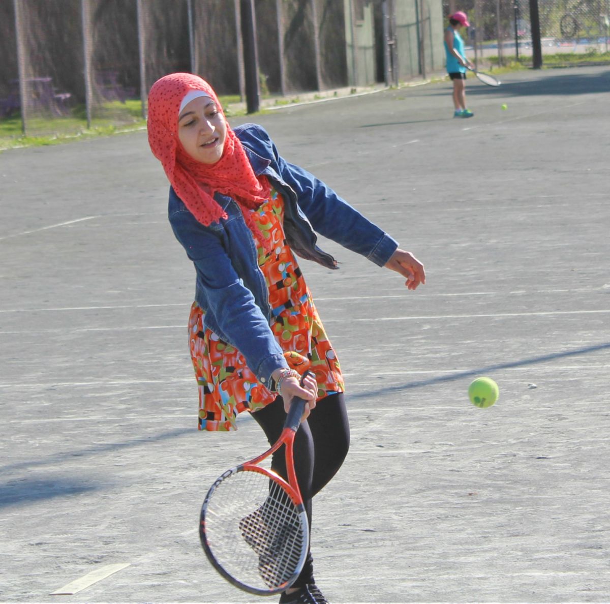 A young newcomer attempts to hit a tennis ball