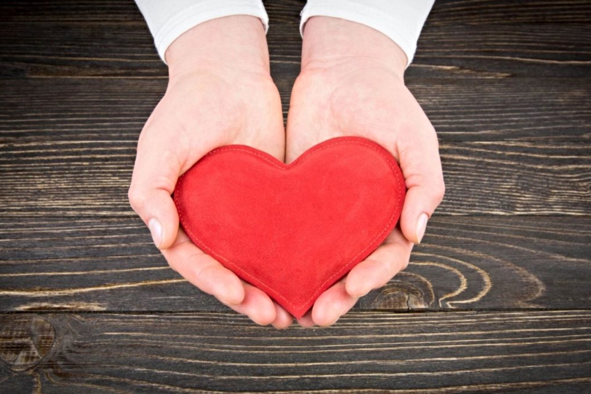 Hands holding a wooden heart